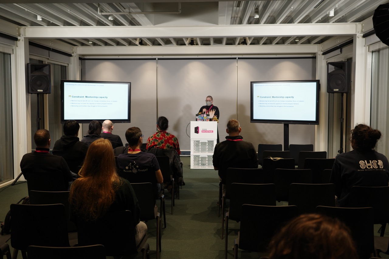 A young white femme person, Anna e só, speaks about Outreachy constraints at FOSS Backstage.